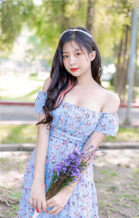 Hình ảnh thiếu nữ xinh đẹp với bộ đầm hoa trên tay cầm bó hoa màu tím